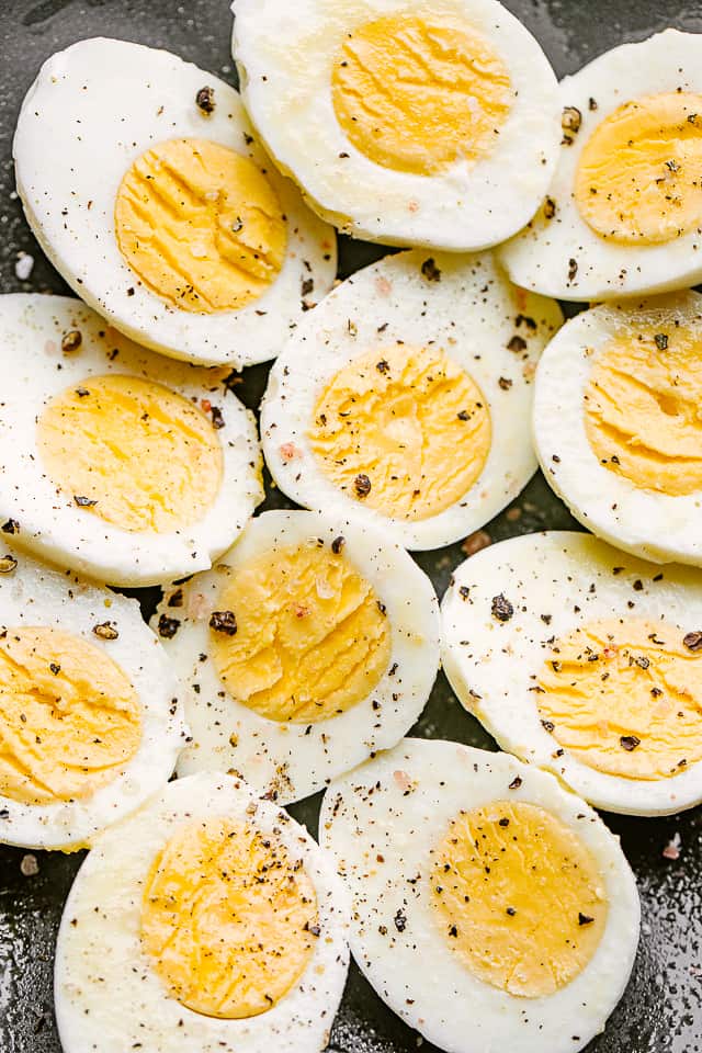 Plate of hard boiled eggs cut in half and garnished with cracked black pepper.