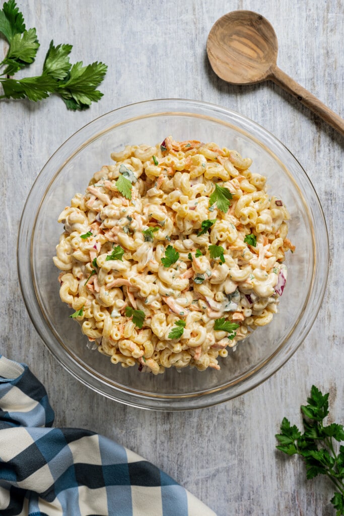 Hawaiian mac salad in a mixing bowl near a wooden spoon.