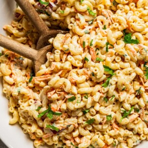 Two wooden spoons in a bowl filled with Hawaiian Macaroni Salad.