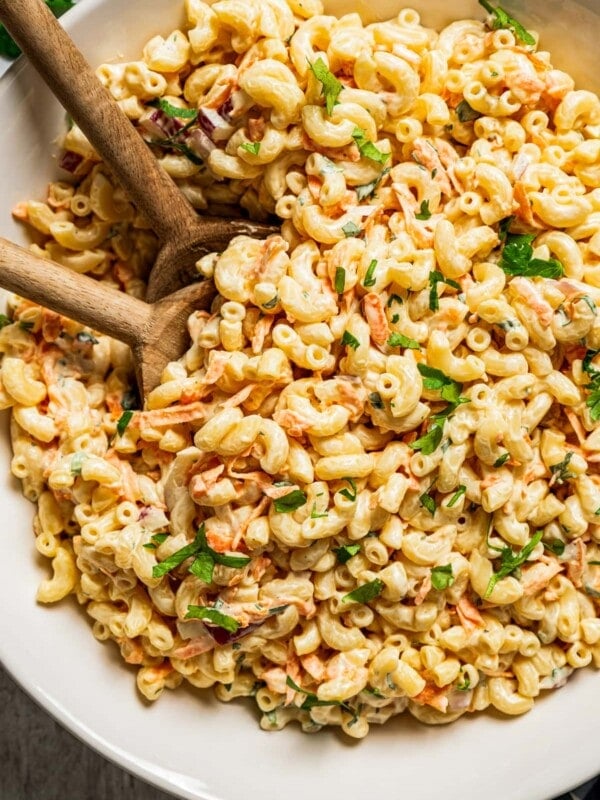 Two wooden spoons in a bowl filled with Hawaiian Macaroni Salad.