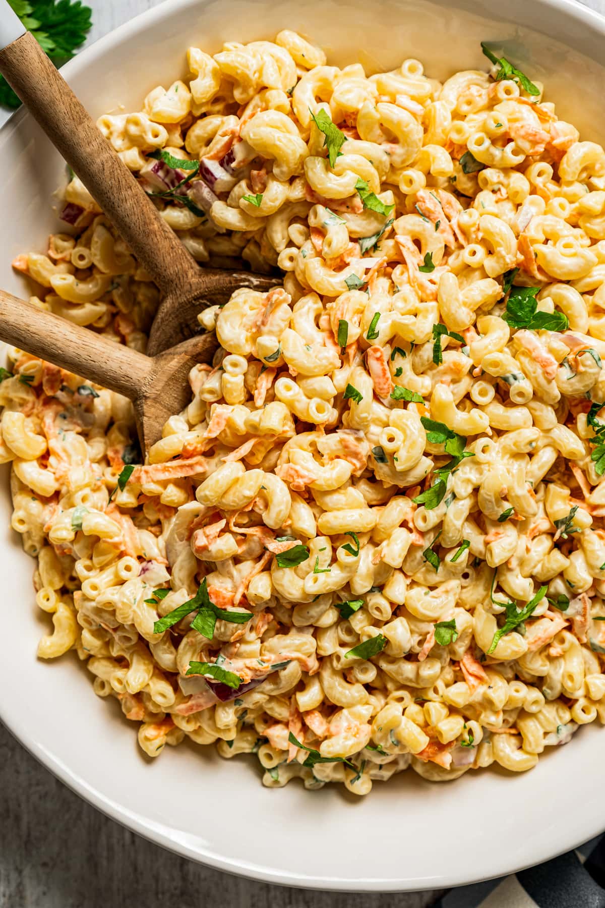 Two wooden spoons in a bowl filled with Hawaiian Macaroni Salad.