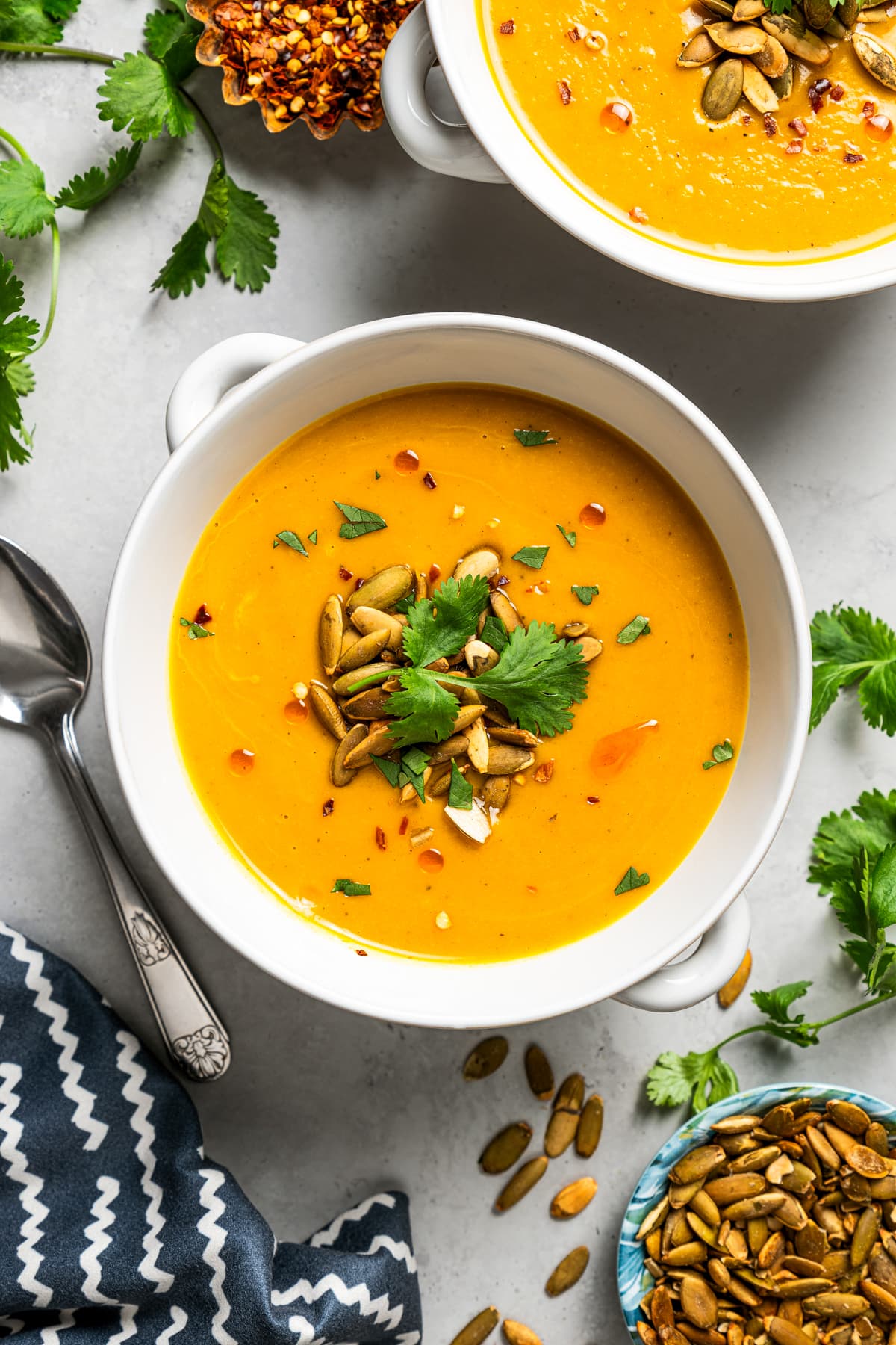 Overhead image of two bowls of soup garnished with pepitas.