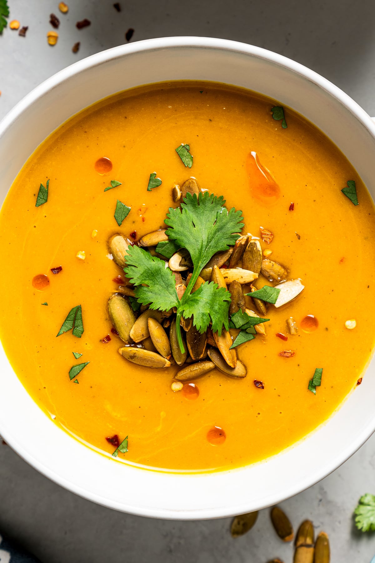 Close-up photo of Instant Pot butternut squash soup served in a bowl and garnished with pepitas and parsley.