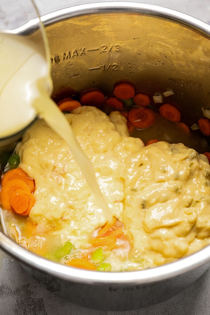 Adding chicken broth to an Instant Pot full of sauteed veggies, cream of chicken, and cream of celery.