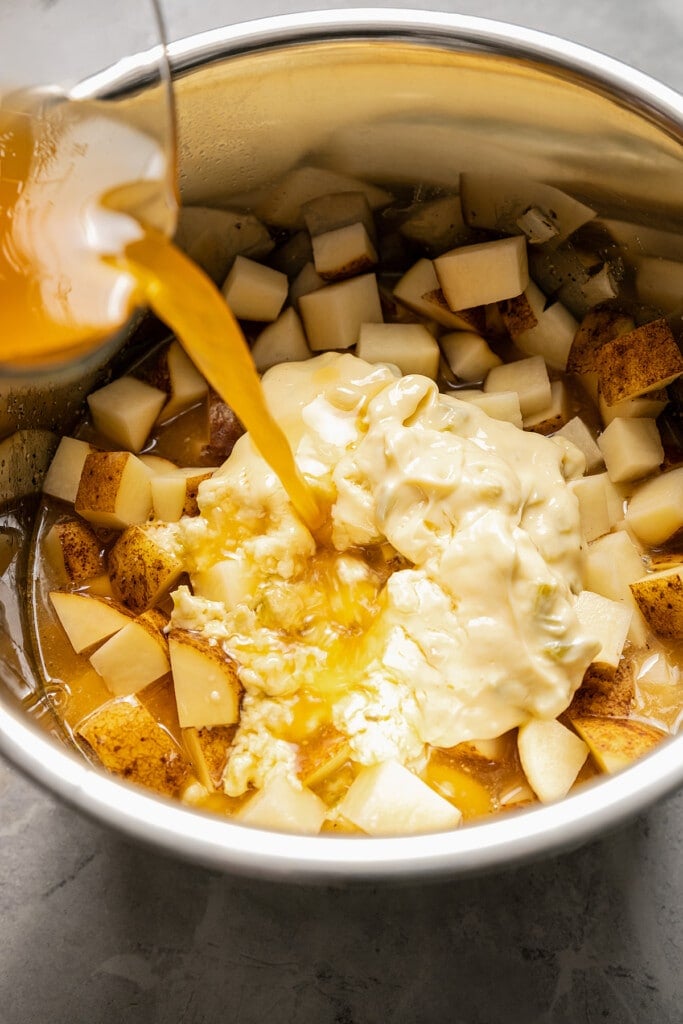 Adding chicken broth, cream of chicken soup, and potatoes to an Instant Pot.