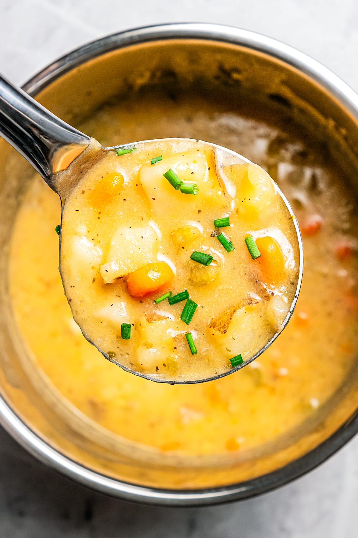 Holding a ladle full of Instant Pot potato soup up to the camera.