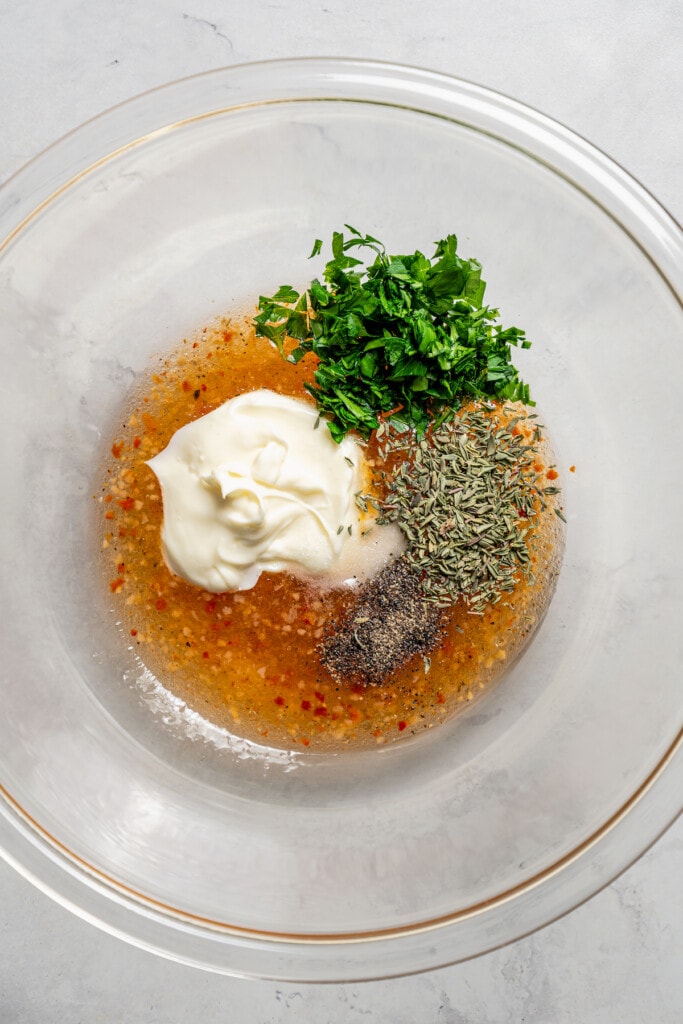 Adding ingredients for Italian dressing marinade to a mixing bowl.