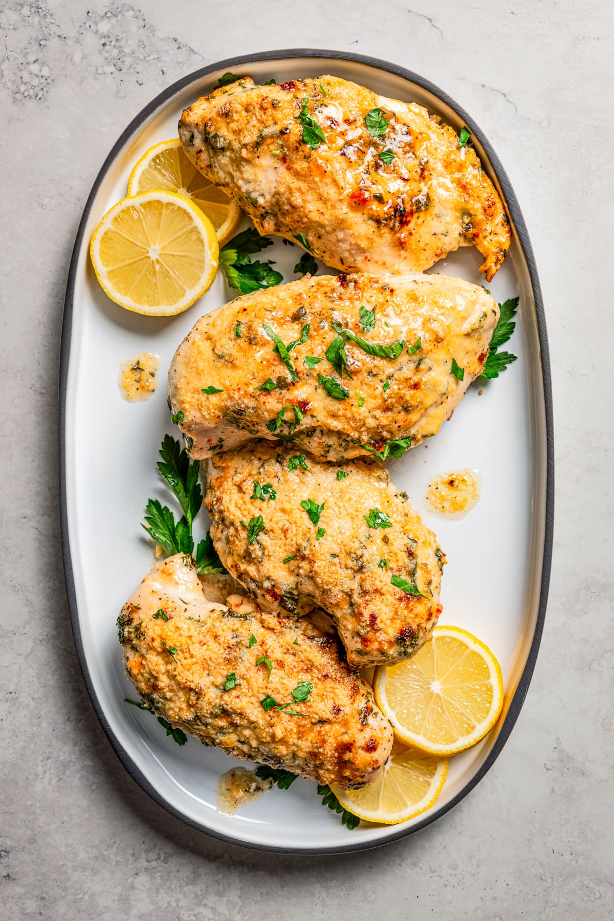 Italian dressing chicken on a serving platter with lemon slices.