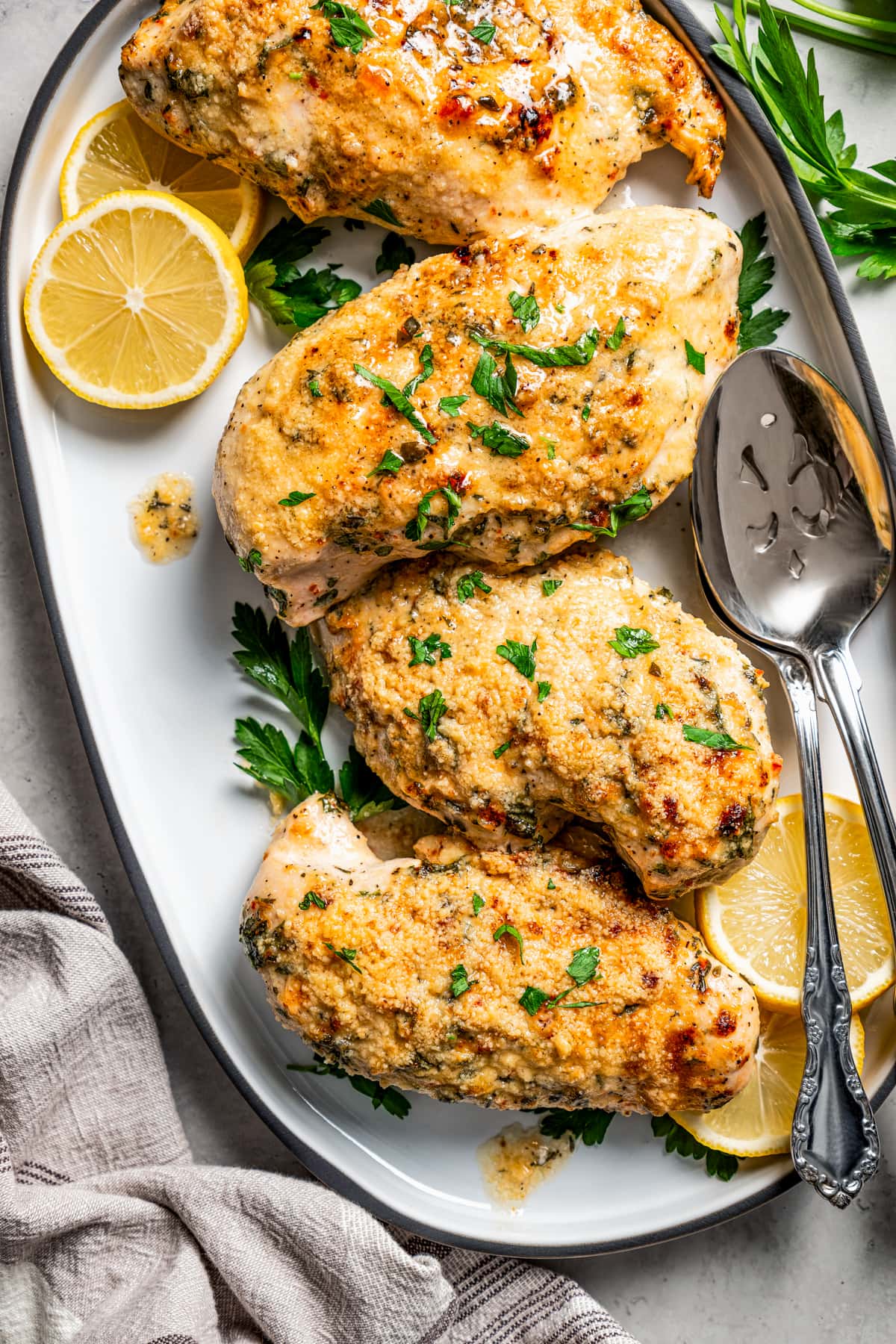 Italian dressing chicken on a serving platter with serving spoons.