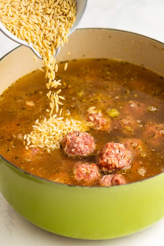 Adding the meatballs and pasta to the pot.