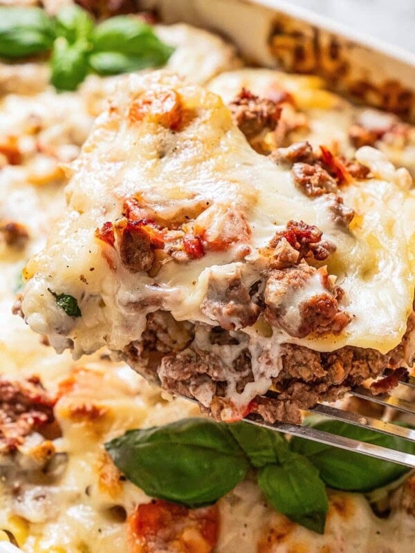 Holding up a slice of lasagna bolognese with a spatula.