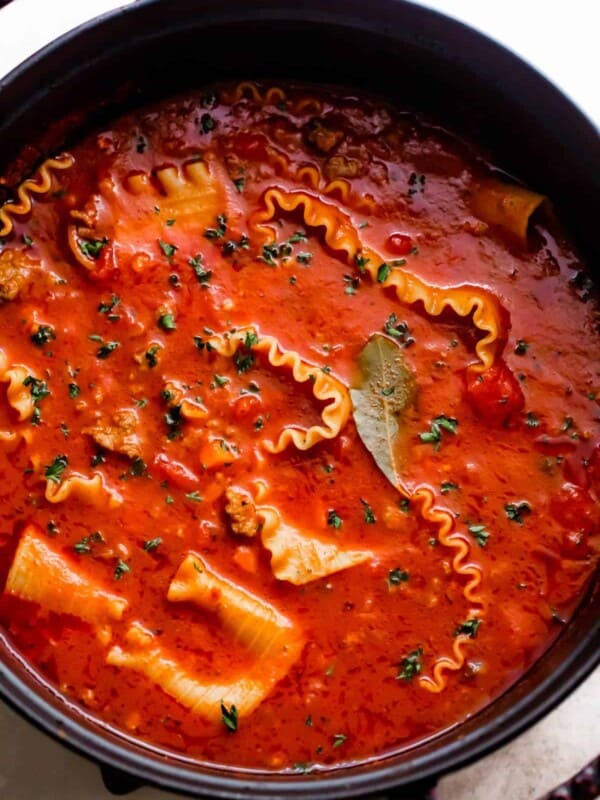 overhead shot of a dark dutch oven filled with lasagna noodles in tomato broth