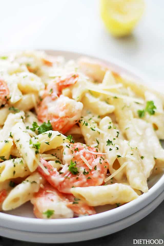 Lemon shrimp pasta in a white bowl topped with parmesan cheese and fresh minced parsley.