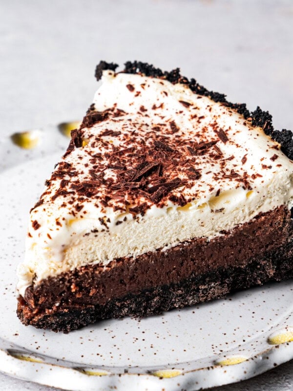 A slice of chocolate pie garnished with chocolate shavings and served on a white plate.