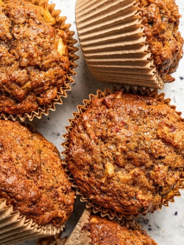 Photo of five morning glory muffins set on a light-colored surface.