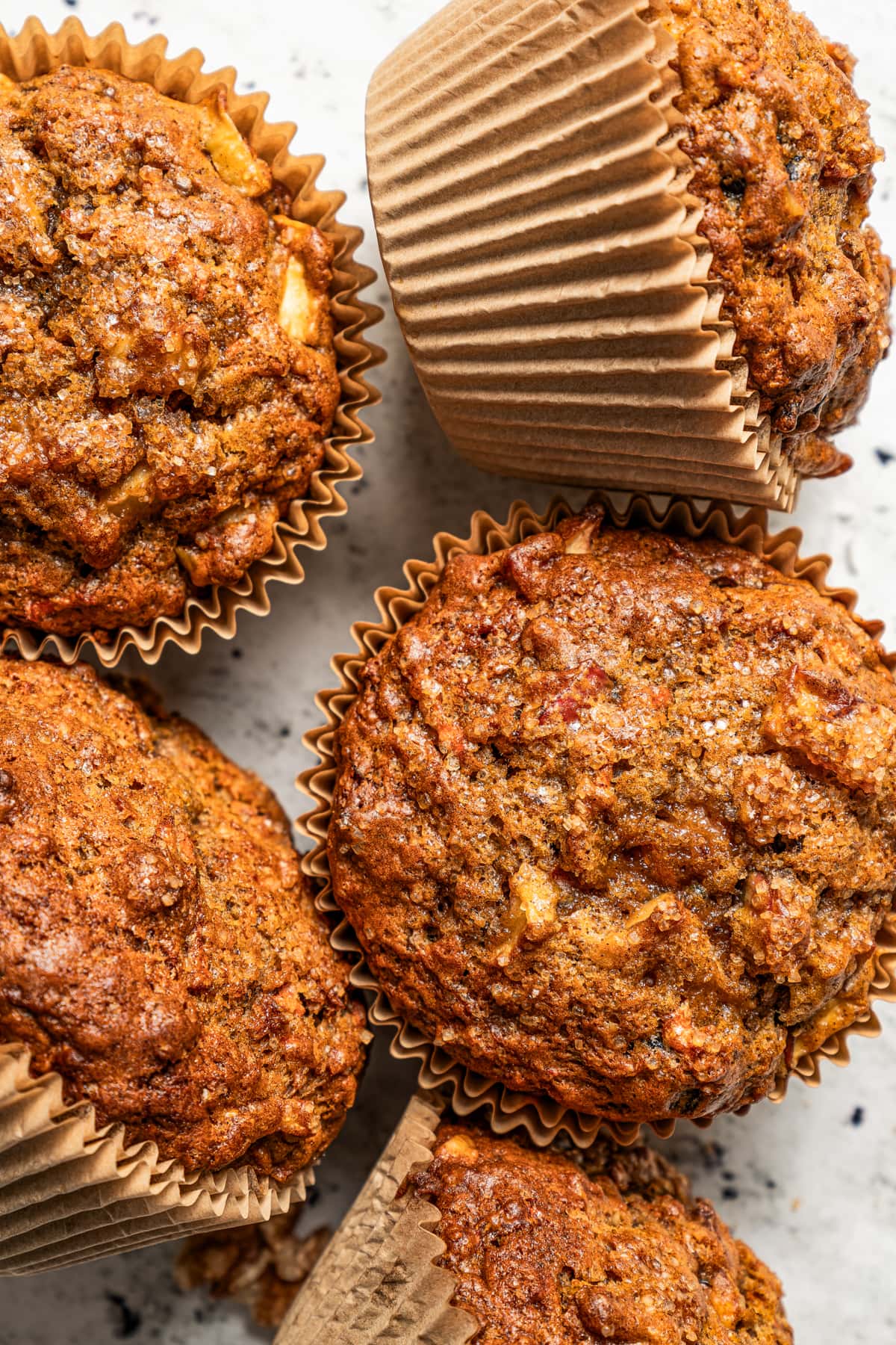 Photo of five morning glory muffins set on a light-colored surface.