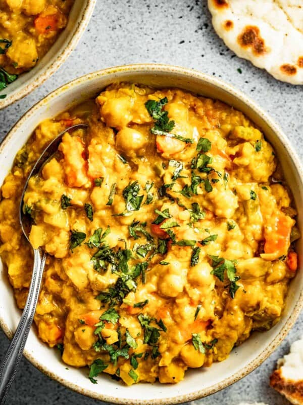 Mulligatawny stew in a bowl with a spoon and naan.