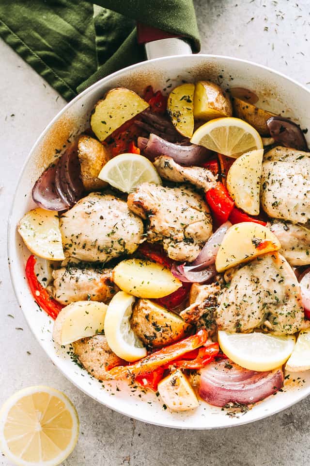 Chicken and veggies in a skillet and topped with lemon and garlic marinade.