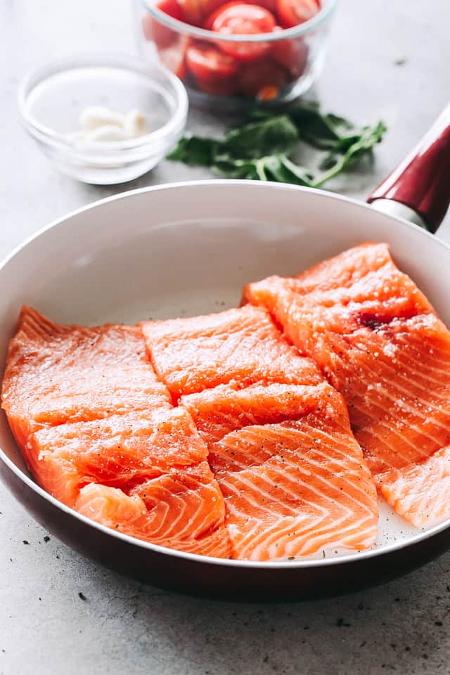 Three raw fish fillets in a skillet.