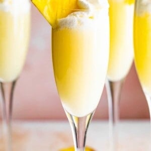 up close photo of champagne flutes with pineapple mimosas