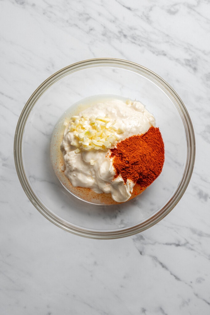 Combining the ingredients for lemon-garlic aioli in a mixing bowl.