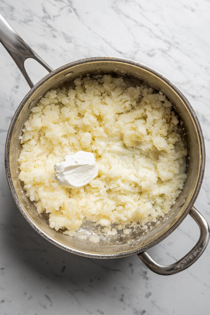 Adding sour cream and milk to mashed potatoes.