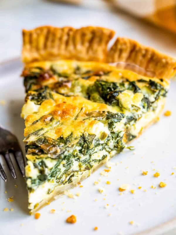 Slice of spinach quiche on a plate.