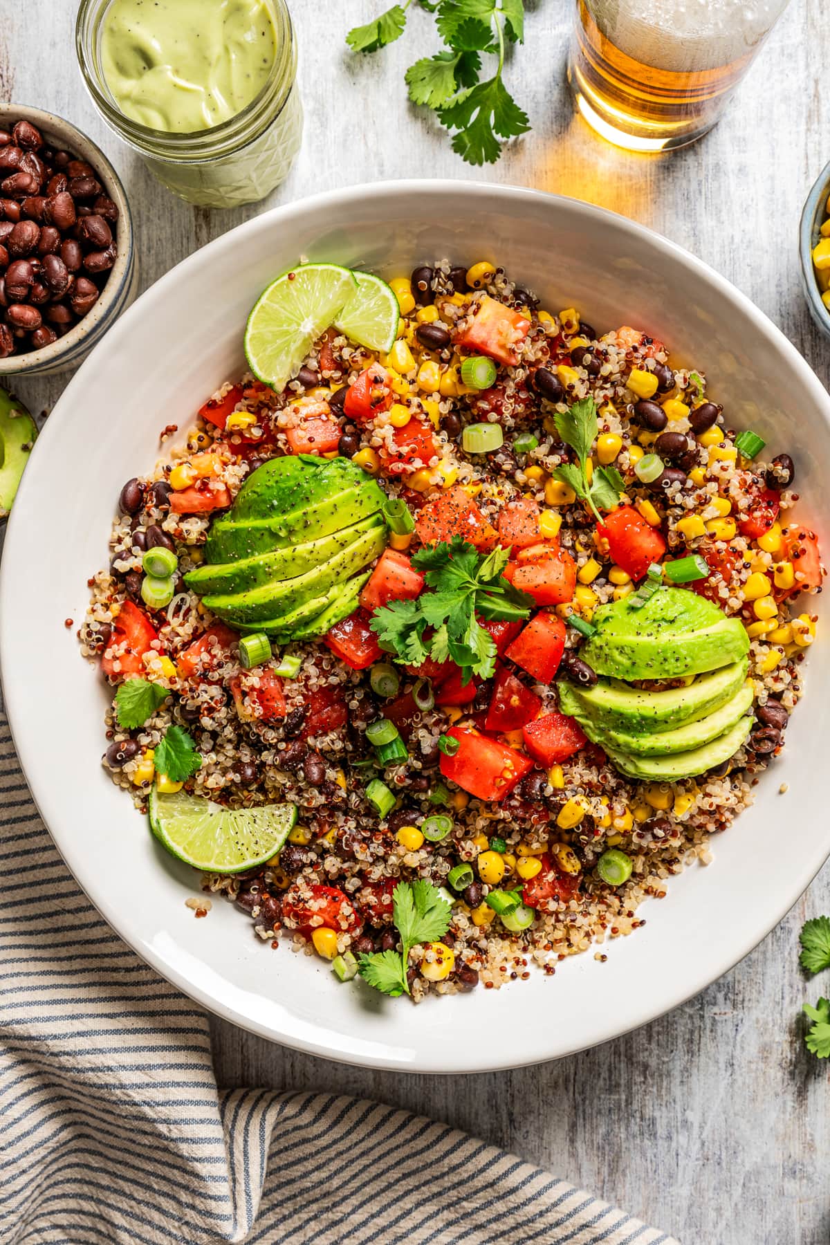 Overhead image of Quinoa Southwestern Salad in a salad bowl topped with sliced avocados and slices of lime.