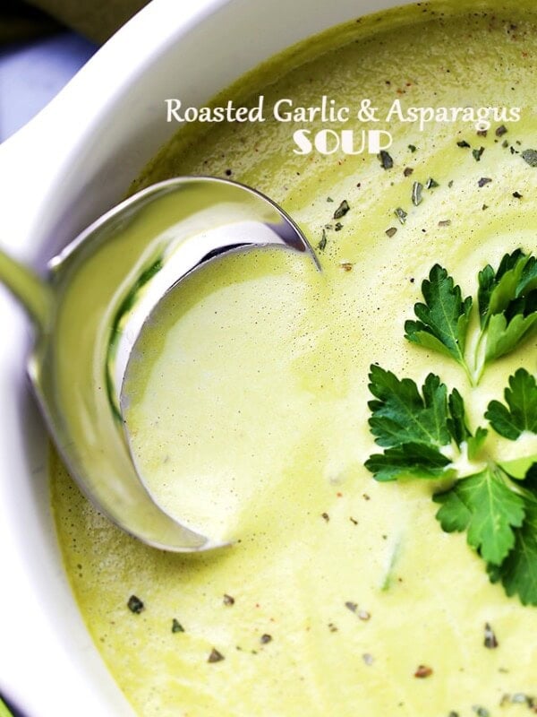 A Ladle spooning out creamy asparagus soup with garlic.