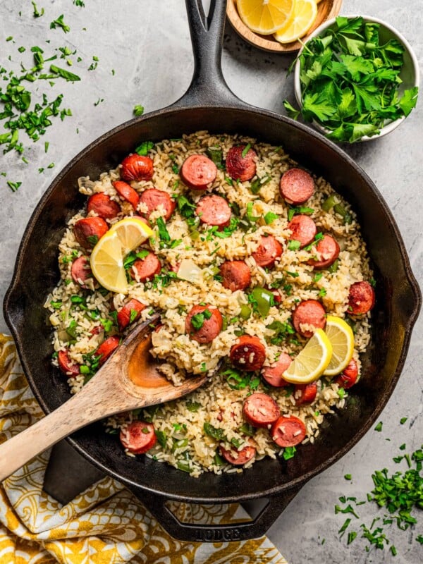 Stirring through rice and sausage with a wooden spoon.