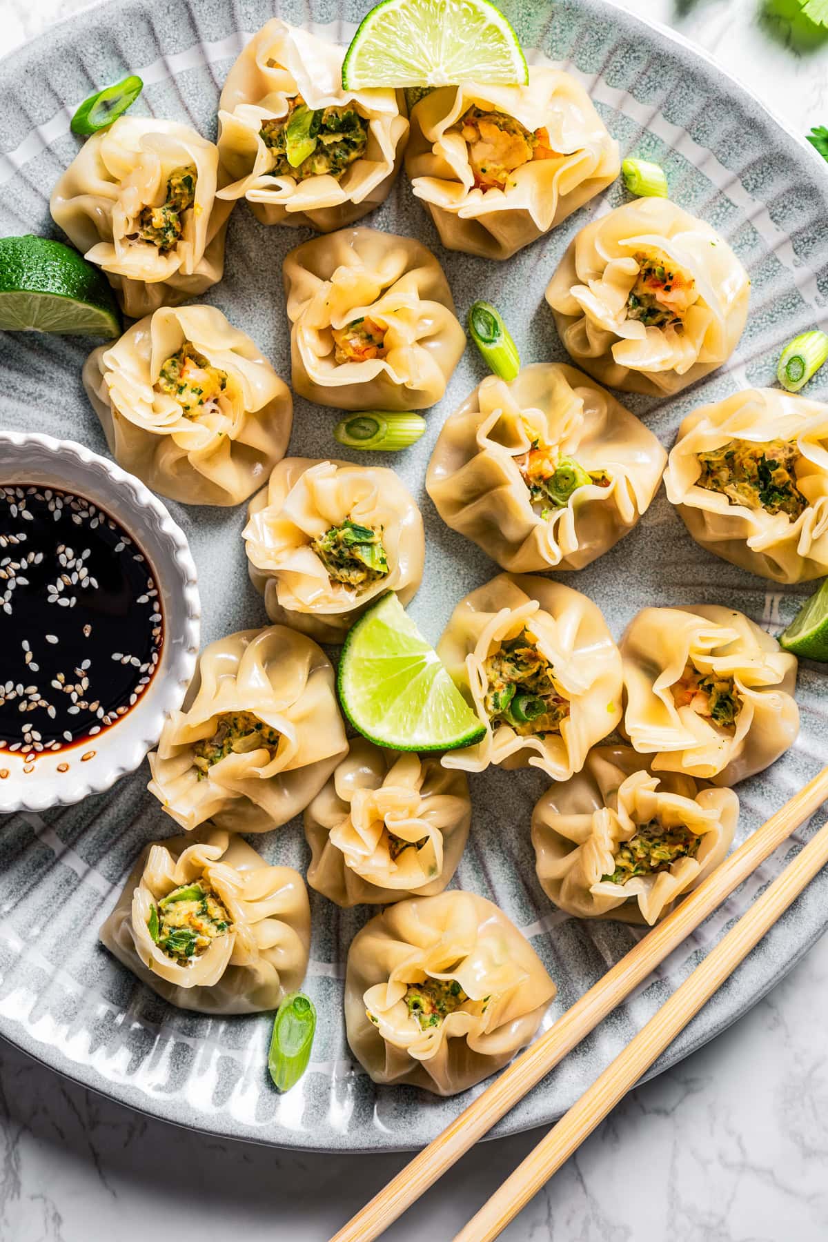 Shumai served on a plate with a bowl of soy sauce on the side.