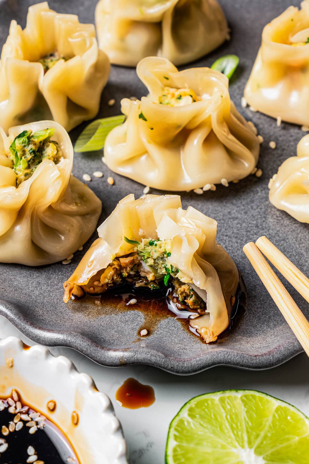 A bite is missing from a shrimp dumpling to expose the filling. More shrimp shumai are arranged on the plate.