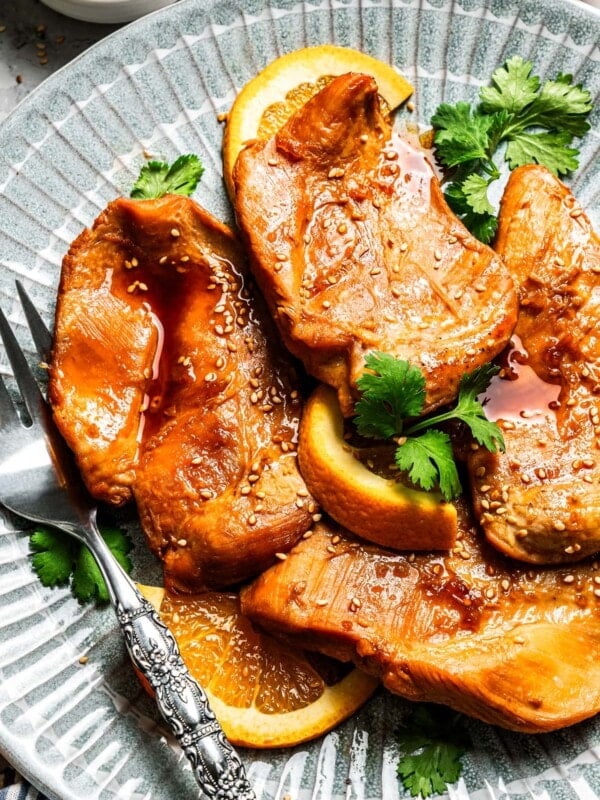 Crockpot orange chicken served on a plate with a fork.