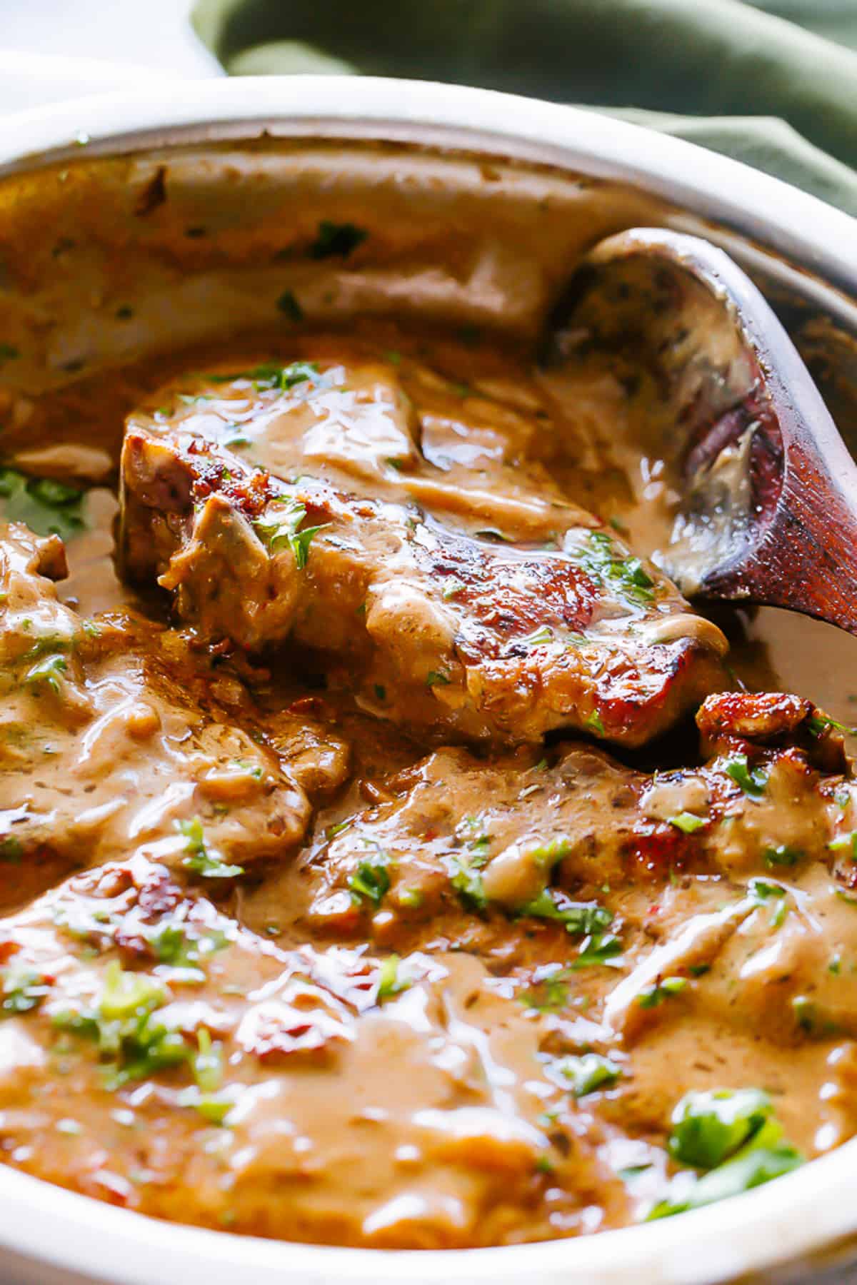 Gravy and bone-in seared pork chops in a skillet.