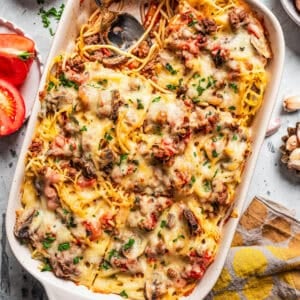 Overhead view of a baked spaghetti casserole in a baking dish, with a serving missing from the corner.