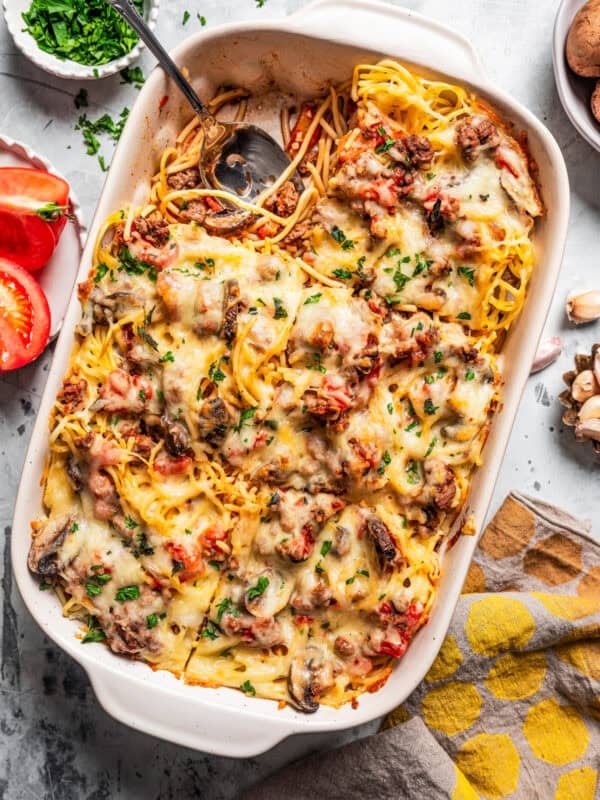 Overhead view of a baked spaghetti casserole in a baking dish, with a serving missing from the corner.