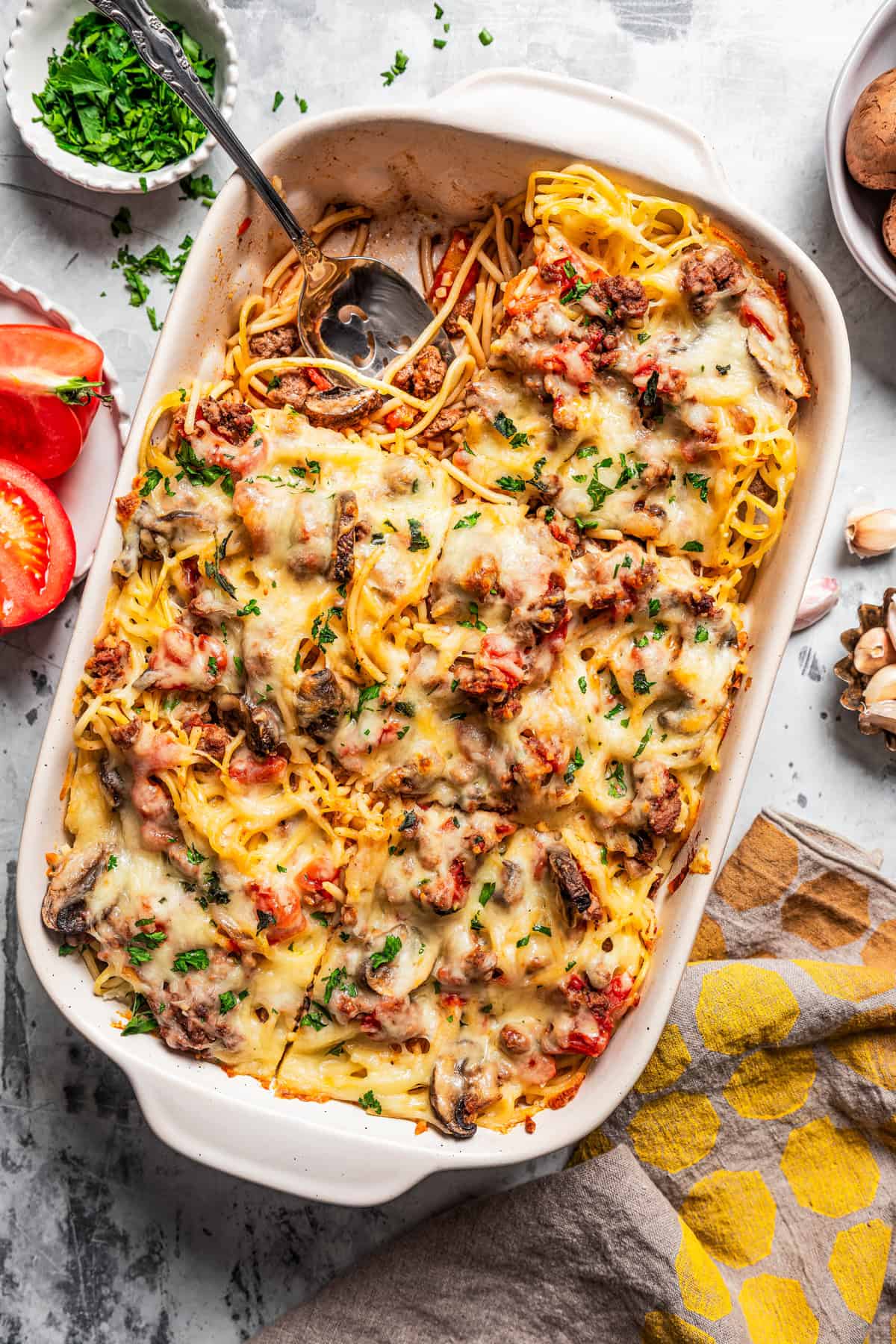 Overhead view of a baked spaghetti casserole in a baking dish, with a serving missing from the corner.