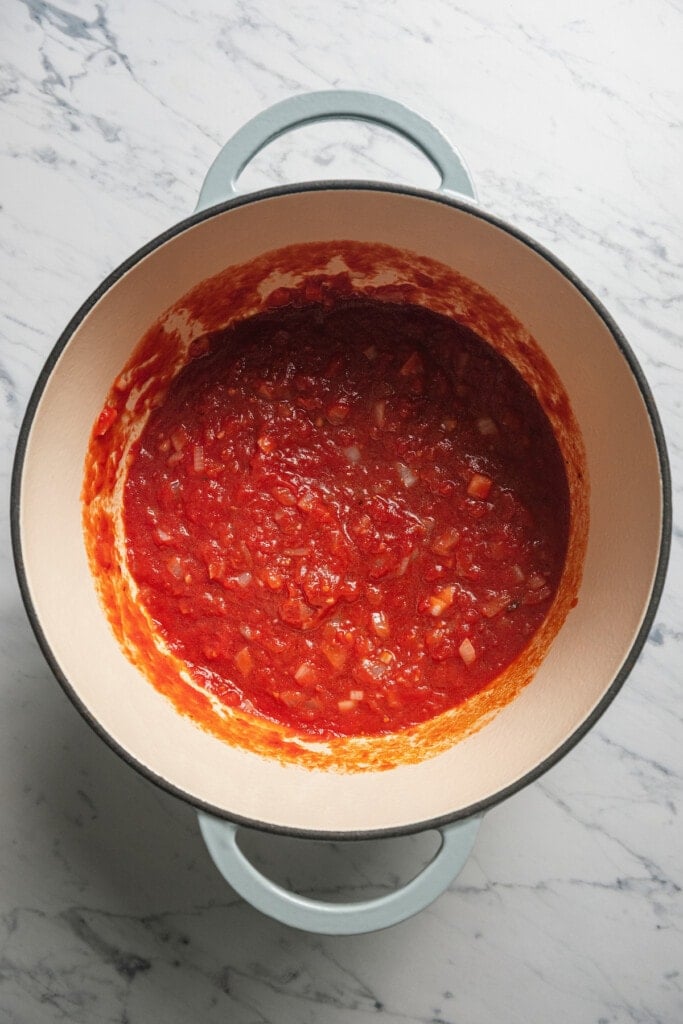 Stirring in the canned tomatoes and tomato sauce. 