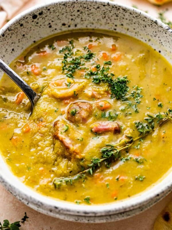 Split pea soup in a bowl with chunks of ham and herbs on top