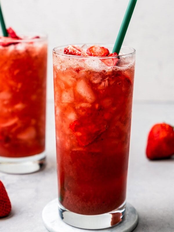 Two homemade Strawberry Acai Refreshers served in drinking glasses garnished with freeze-dried strawberries.