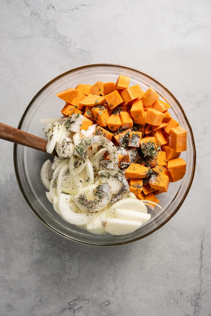 Sweet potatoes, onions, and olive oil in a bowl.