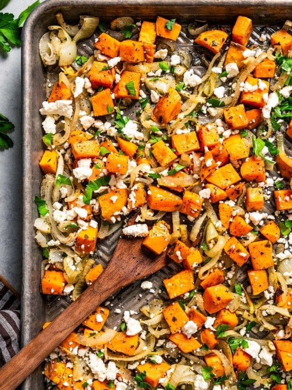 Stirring through cubed sweet potatoes on a baking sheet.