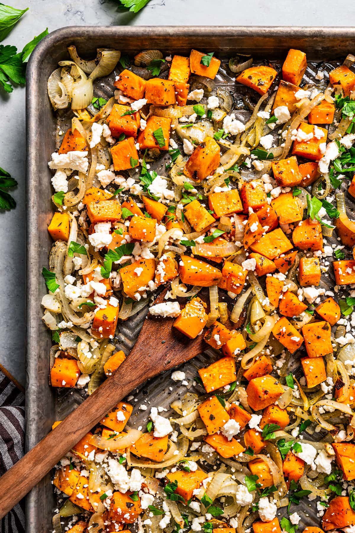 Stirring through cubed sweet potatoes on a baking sheet.