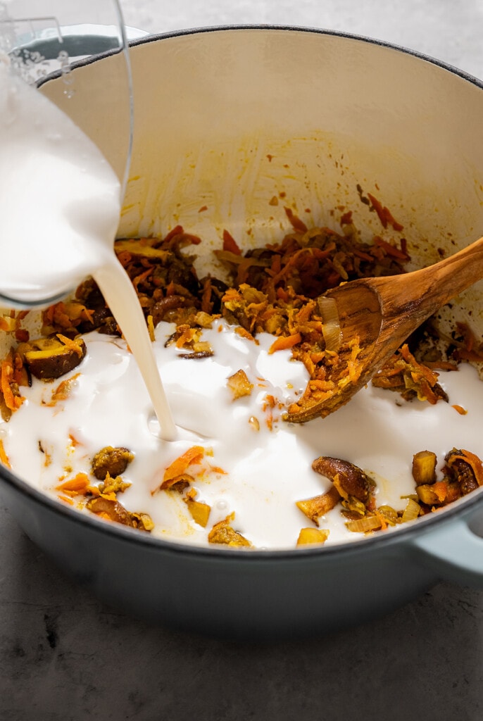 Adding coconut milk to sauteed aromatics, veggies, and curry paste.