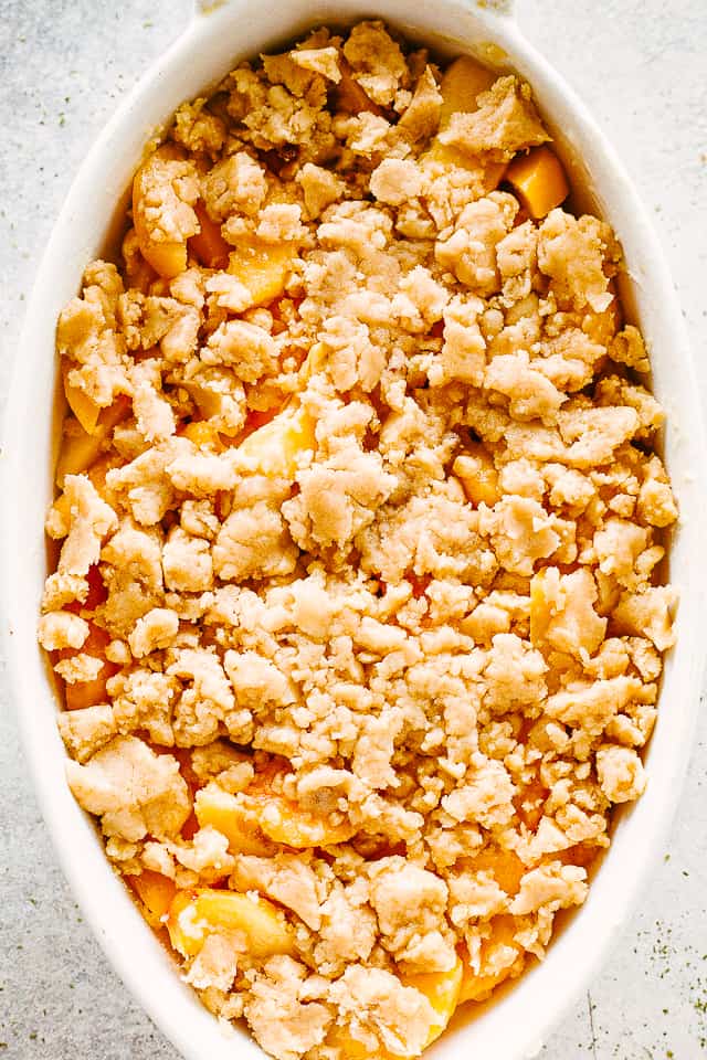 Unbaked peach cobbler with raw crumble topping.