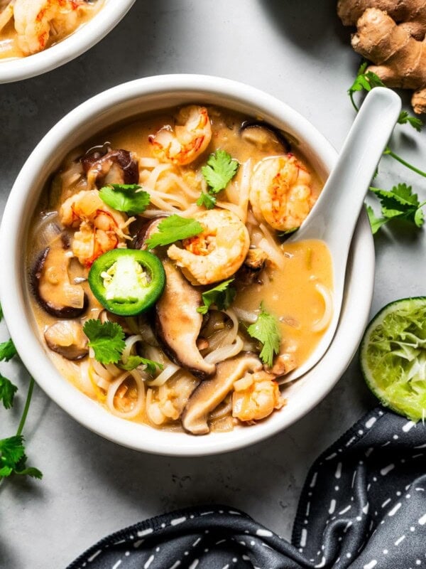 Tom yum noodle soup in a bowl with a lotus spoon.