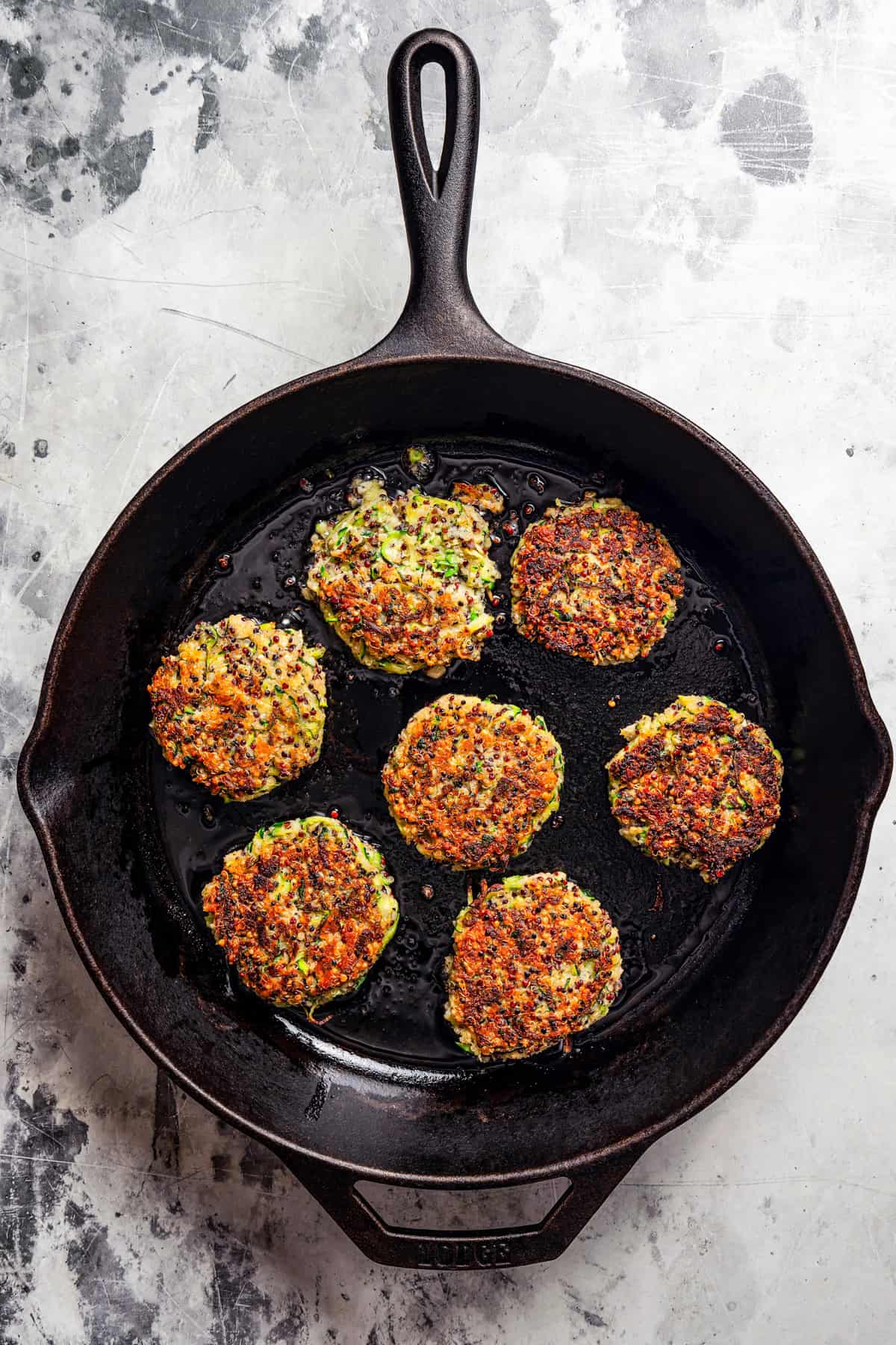 Cooking zucchini cakes in a large skillet.