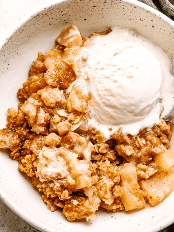 Apple Crumble served in a bowl with vanilla ice cream.